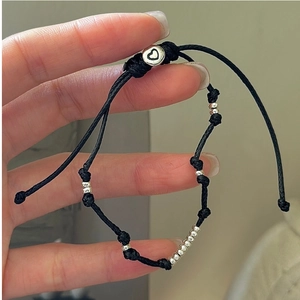 Detailaufnahme des schwarzen geflochtenen Armbands mit Silberperlen und Herz