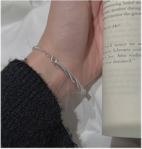Detail of twisted silver bracelet on wrist featuring minimalist S925 sterling silver design