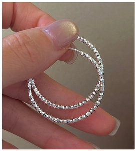 Dettaglio di orecchini a cerchio in argento sterling S925 con finitura sfaccettata lucida