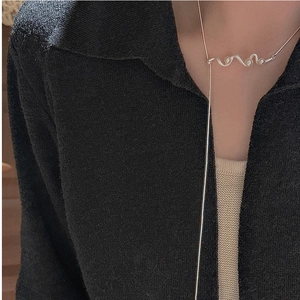 Detail of S925 sterling silver wavy necklace on black knit sweater background