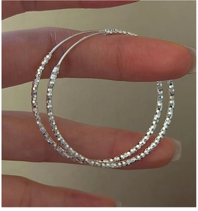Dettaglio di orecchini a cerchio in argento sterling S925 con superficie diamantata lucida