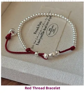Detail of S925 sterling silver beads on a red woven string bracelet in a jewelry box