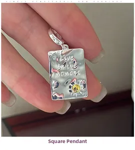 Detailed macro of S925 silver square pendant with hammered texture and engraved lettering