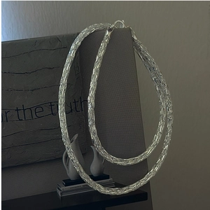 Detail view of S925 sterling silver mesh chain necklace with lobster clasp against a grey wall
