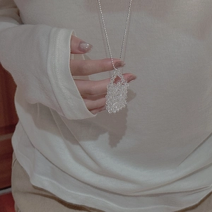 Detail of a minimalist beaded pendant necklace with faceted clear crystals on silver ball chain