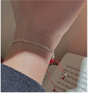 Detail of S925 sterling silver twisted chain bracelet with red cord and small silver bead