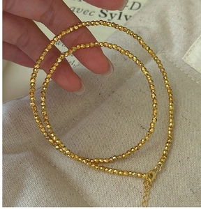 Détail d'un collier de perles dorées facettées avec fermoir mousqueton réglable