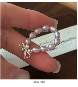 Close-up of pink purple freshwater pearl beaded ring with silver bow on a finger