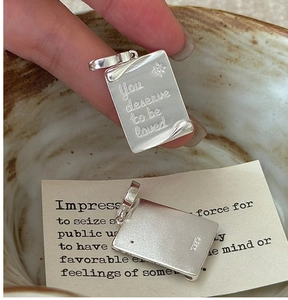 Macro detail of S925 sterling silver book pendant with You Deserve To Be Loved engraving