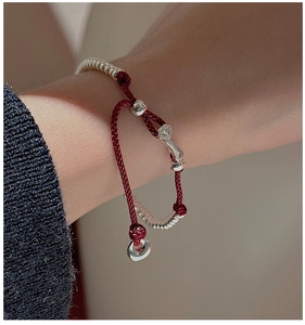 Close-up of S925 silver cat paw pendant on red braided rope bracelet for women