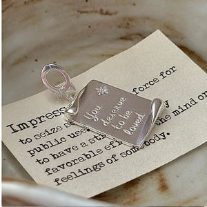 Macro shot of S925 silver scroll pendant with stars and You deserve to be loved engraving