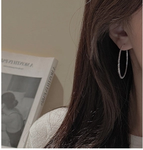Primo piano di orecchini a cerchio in argento sterling S925 con texture scintillante su modella