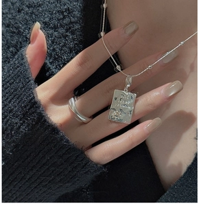 Detail of silver S925 necklace with engraved square pendant and wave ring on a model
