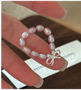 Macro detail of S925 silver bow charm on a handmade light purple pearl beaded ring