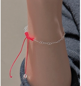 Close-up of S925 sterling silver chain and red woven rope bracelet on a grey knit sleeve