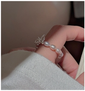 Macro detail of S925 silver bow ring with pink pearls worn on a woman's finger