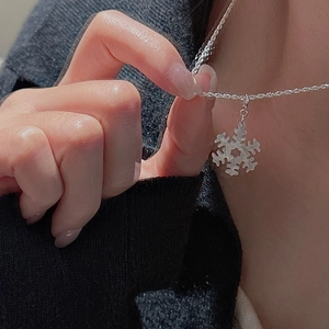Collana con fiocco di neve in argento S925 indossata su un maglione nero
