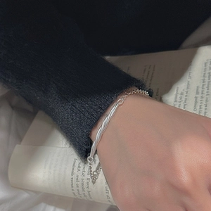 Minimalist S925 sterling silver twist tube bracelet worn by a model in a cozy setting