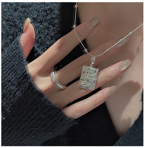 Close-up of S925 silver necklace with engraved rectangle pendant and textured ring