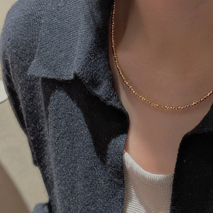Collier minimaliste en argent S925 à perles dorées facettées sur un pull en maille bleu