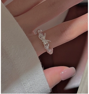 Close-up of S925 silver bow ring with small pink pearls on a woman finger