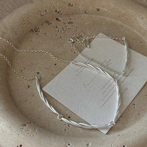 Minimalist S925 sterling silver twisted knot necklace on a stone texture background