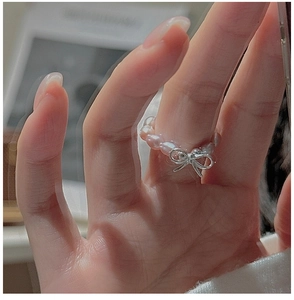 Detailed close-up of S925 silver bow and pink baroque pearl beaded ring on finger