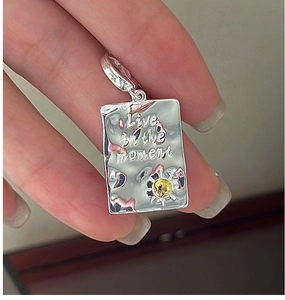 Macro detail of S925 silver rectangle pendant engraved with Live in the moment text