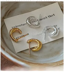 Gros plan de boucles d'oreilles C en argent sterling S925 avec texture martelée or et argent