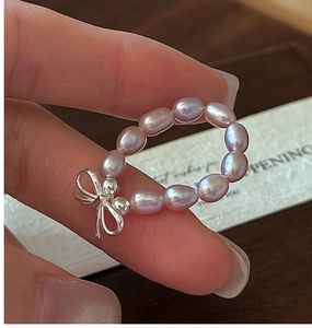Macro detail of the beaded pearl ring featuring a silver bow accent and lilac pearls