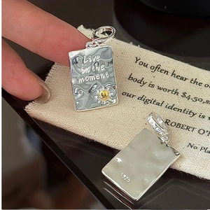 Macro detail of S925 sterling silver rectangular pendant with Live in the moment engraving