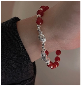 Détail macro du bracelet en perles d'argent S925 avec perles d'agate rouge et charm poisson