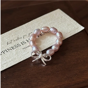 Macro shot of an elastic pearl ring with a silver bow pendant on a card