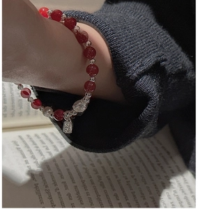 Détail du bracelet en perles d'agate rouge avec breloque cœur en argent sur le poignet