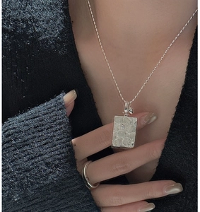 Close-up of S925 sterling silver rectangular pendant with embossed daisy flower and zircon