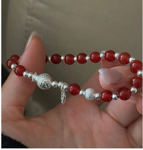 Détail de perles d'agate rouge avec breloque poisson en argent S925 sur un bracelet chic
