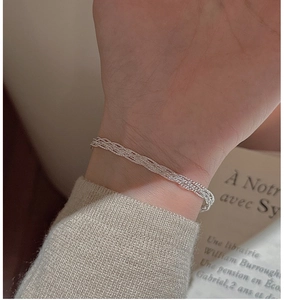 Close-up of a multi-strand woven silver bracelet on a wrist with French retro aesthetic