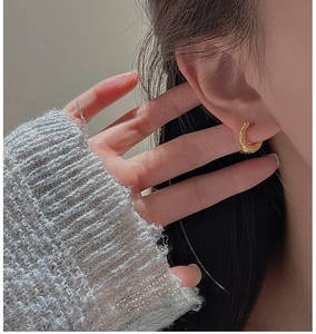 Gros plan de boucles d'oreilles dorées rondes avec texture martelée sur un mannequin
