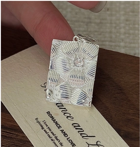 Macro shot of S925 sterling silver rectangular pendant with embossed floral daisies