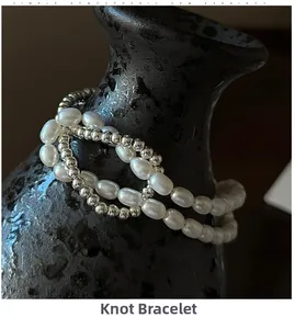 Détail d'un bracelet en argent S925 avec perles baroques sur un vase en céramique noire