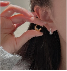 Détail de boucles d'oreilles créoles dorées et argentées à texture martelée sur modèle