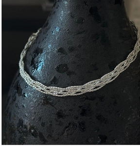 Macro detail of braided S925 sterling silver chain with liquid metallic texture