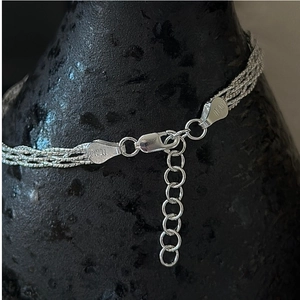 Macro shot of silver woven bracelet with lobster clasp and Italy engraving details
