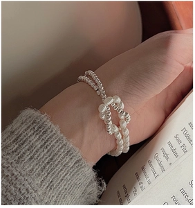 Détail d'un bracelet double rang en argent S925 avec perles et nœud métallique élégant