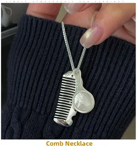 Detail of S925 silver necklace with mini comb and white shell charms on blue sweater