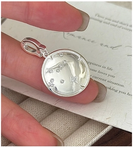 Détail macro du pendentif étoile en argent S925 serti de zircones tenu entre les doigts