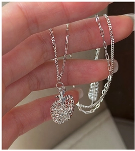 Macro shot of S925 sterling silver apple pendant with intricate woven texture and layered chain