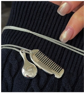 Macro shot of S925 sterling silver sweater necklace with mini mirror and comb charms
