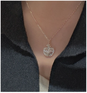 Detail of apple-shaped silver pendant necklace with unique textured finish on a model