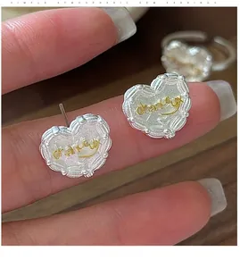 Macro shot of S925 silver heart earrings with gold chanceux text and beaded edge
